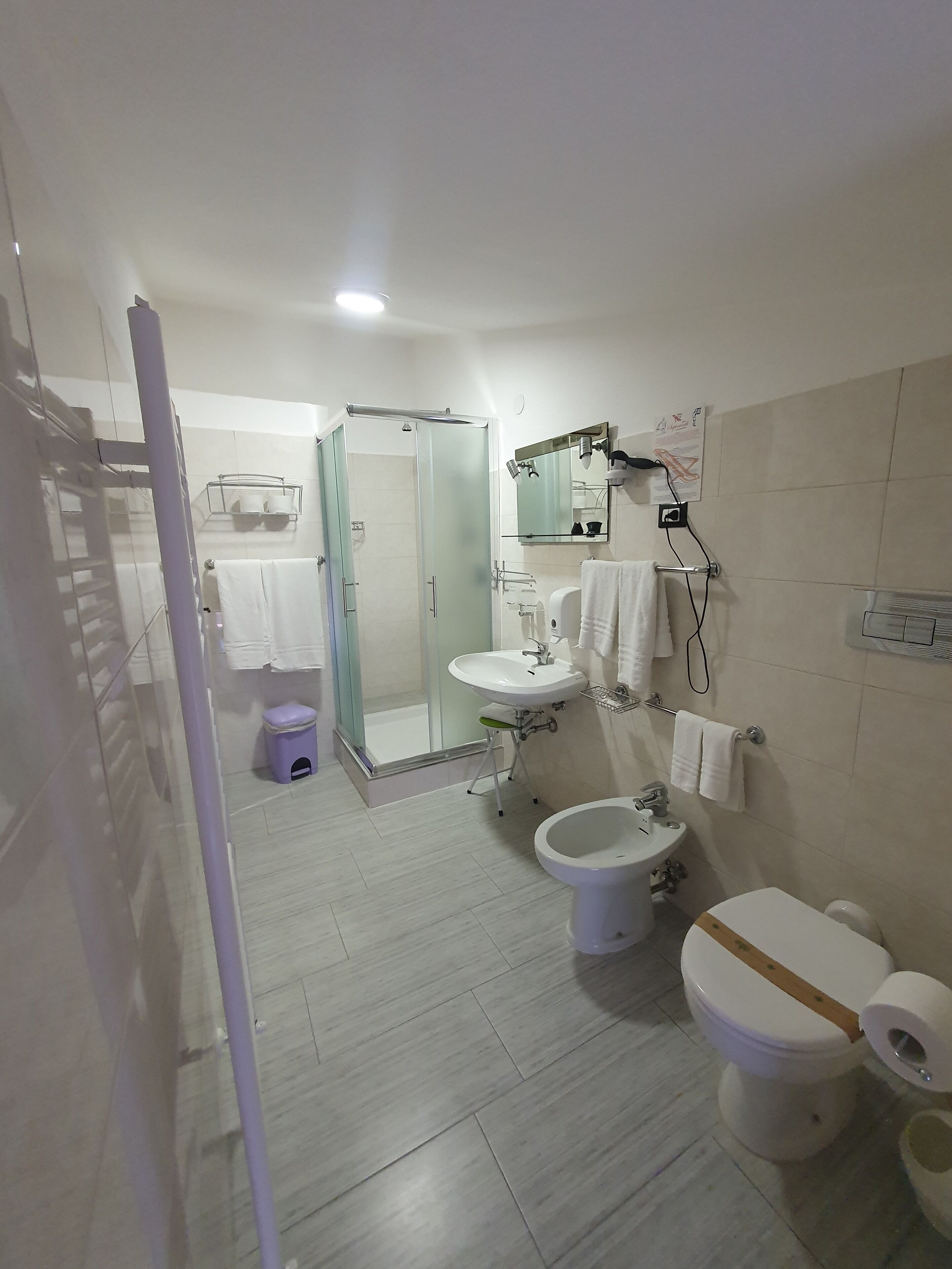 Un baño moderno con cabina de ducha de vidrio, lavabo blanco, inodoro y bidé.