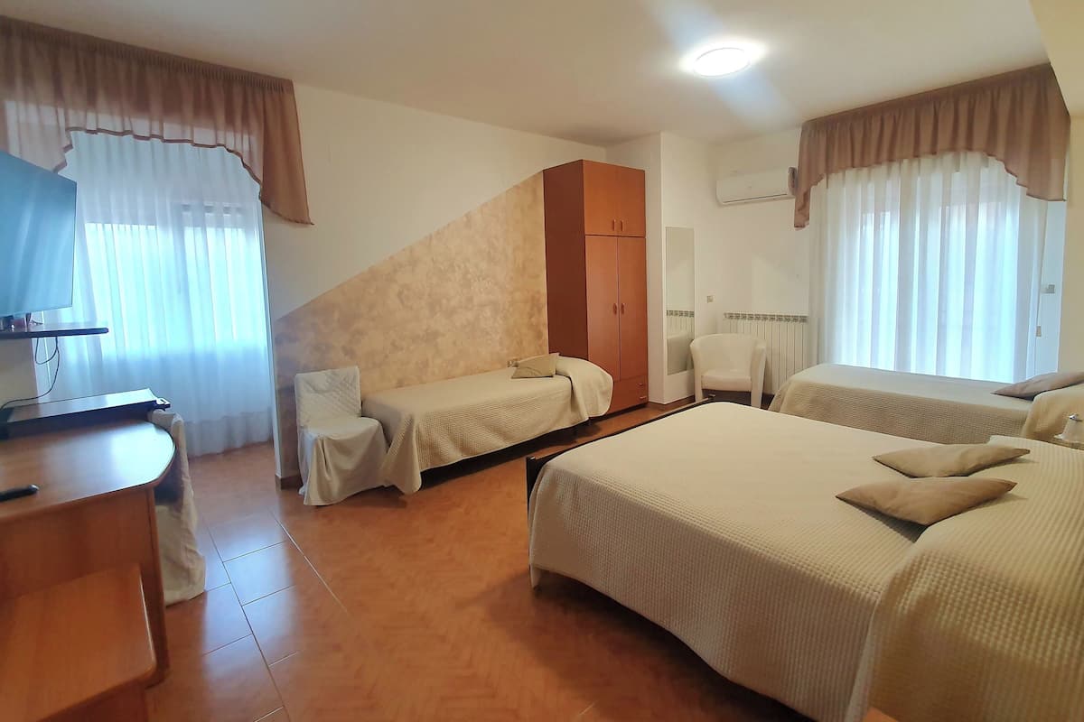 A hotel room with two beds, a desk, a chair, and a TV.