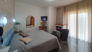 A hotel room with a bed, a TV, a fireplace, and a window with curtains. - Hotel Supersonik (Acri)