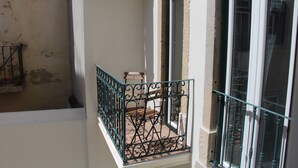 A balcony with a wrought iron railing, a wooden bench, and a window with a view of the interior. - DoBairro Suites at Bairro Alto (Lisbon)