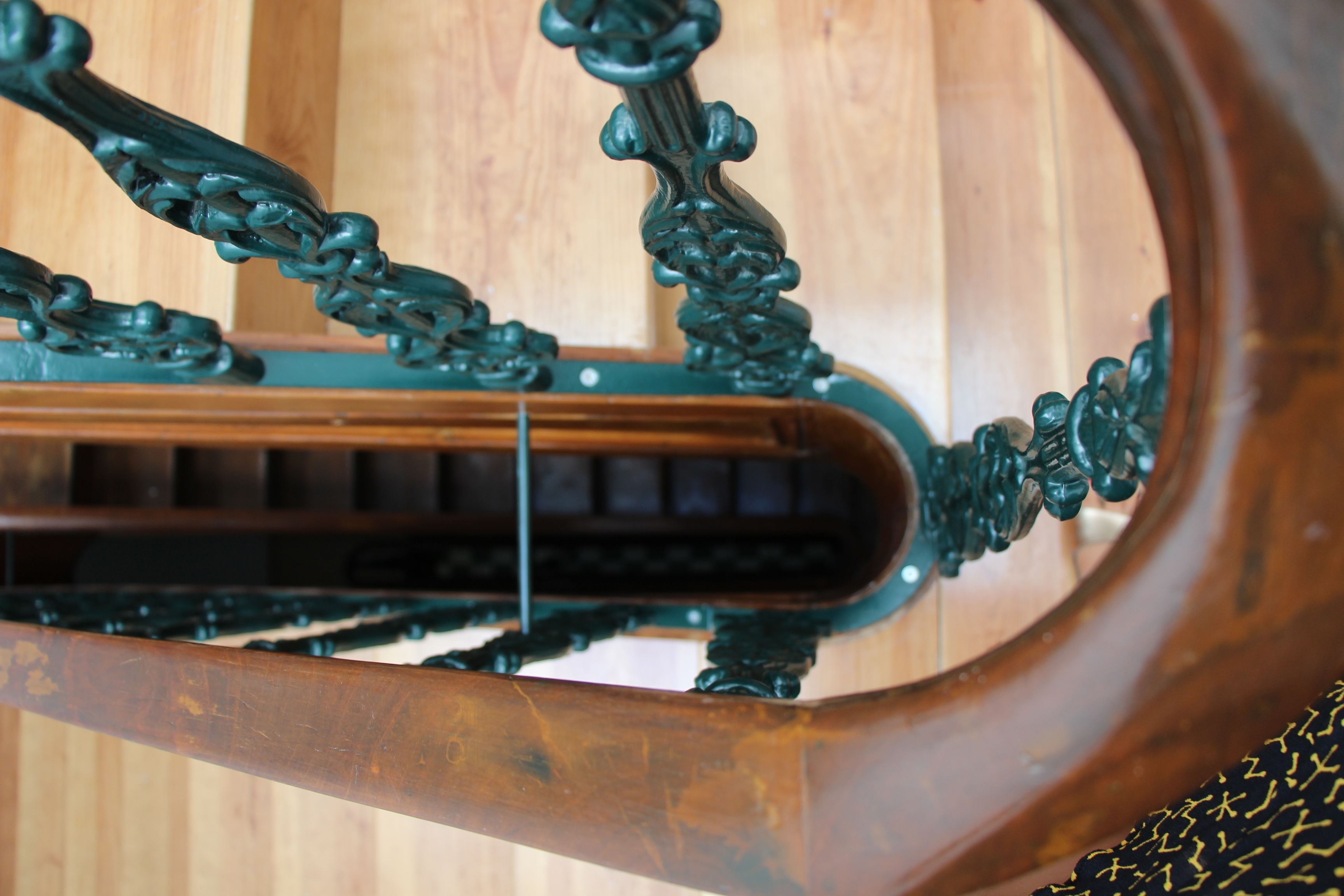 A close-up of a wooden chair with ornate metalwork and a metal frame.