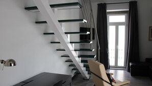 A modern living room with a staircase, a desk, and a chair. - DoBairro Suites at Bairro Alto (Lisbon)