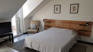 A modern bedroom with a large bed, a television, and a chair. - DoBairro Suites at Bairro Alto (Lisbon)