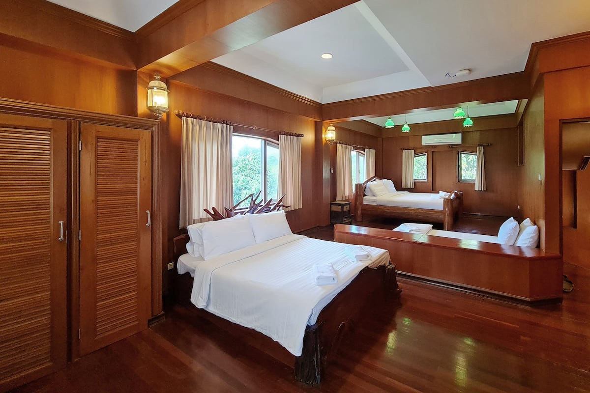 A spacious bedroom with a large bed, a wooden wardrobe, and a small bedside table.