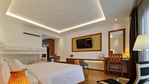 A modern hotel room with a large bed, a desk, a chair, a TV, and a lamp. - Phuphaphung Resort (Suan Phueng)
