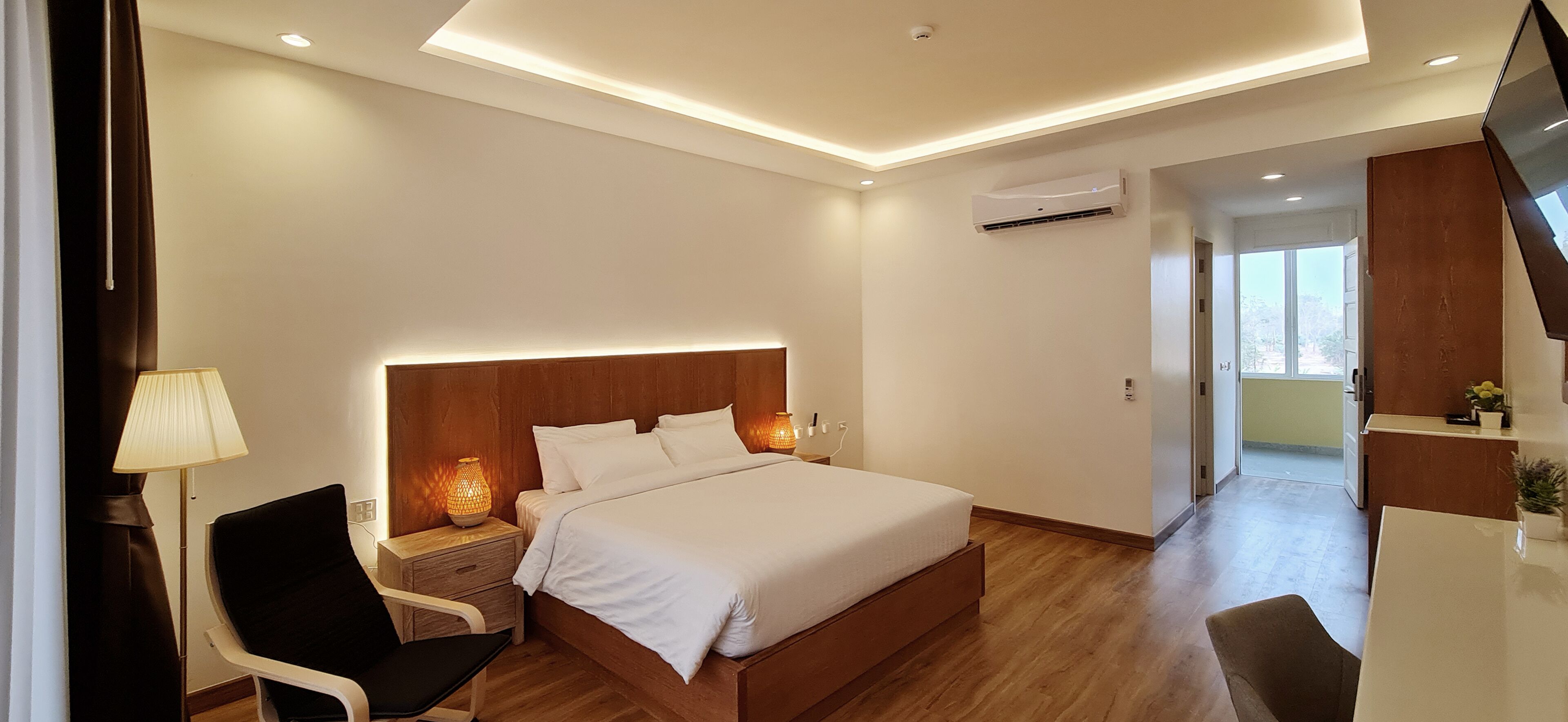 A modern hotel room with a wooden bed, a desk, and a chair.