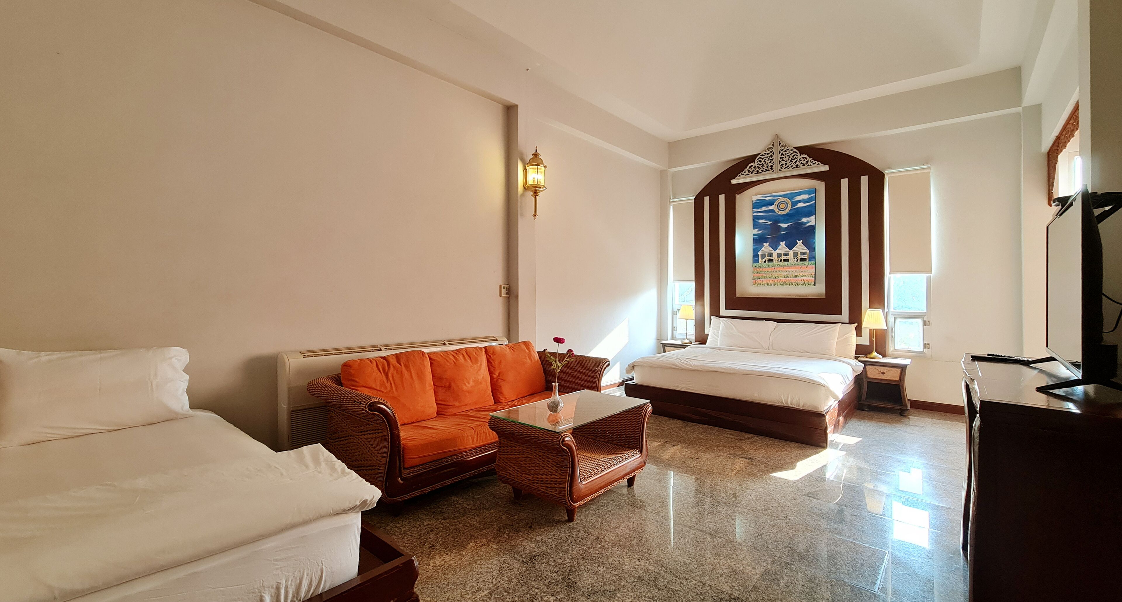 Ein Hotelzimmer mit einem Bett, einem Sofa, einem kleinen Tisch, einer Lampe und einem Gemälde an der Wand.