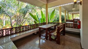 A covered outdoor seating area with a bench, a fire extinguisher, and a view of lush greenery. - Phuphaphung Resort (Suan Phueng)