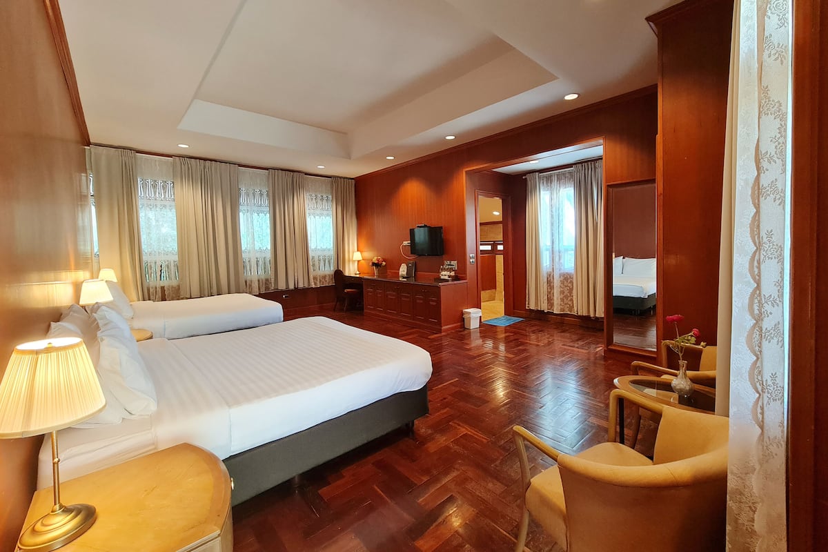 A hotel room with two beds, a desk, a TV, and a chair.