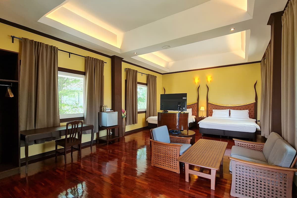 A hotel room with a bed, a desk, a TV, a sofa, and a chair.