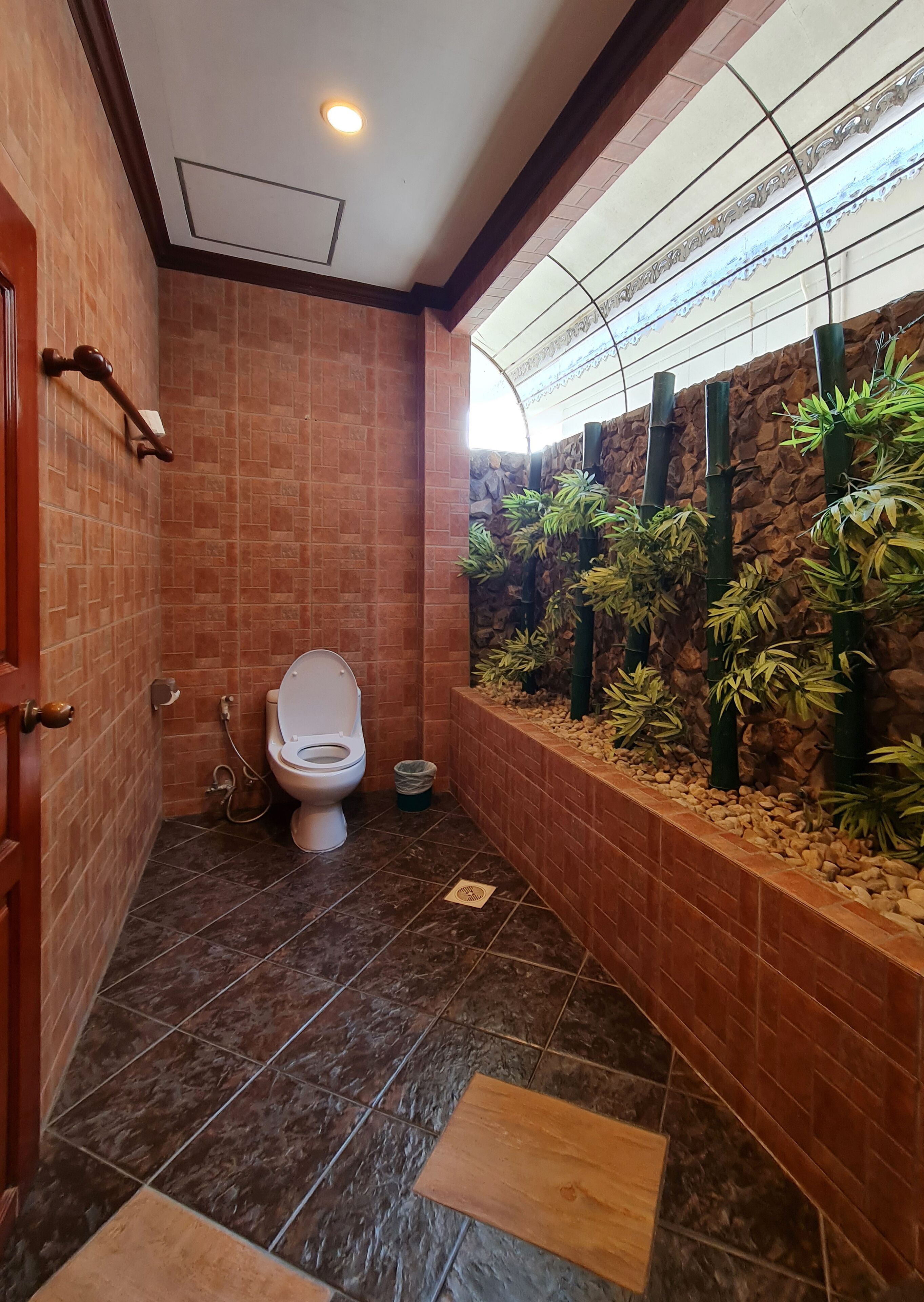 Un baño con un inodoro, un secador de manos y un cubo de basura.