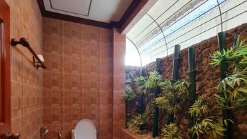 Un baño con un inodoro, un secador de manos y un cubo de basura.