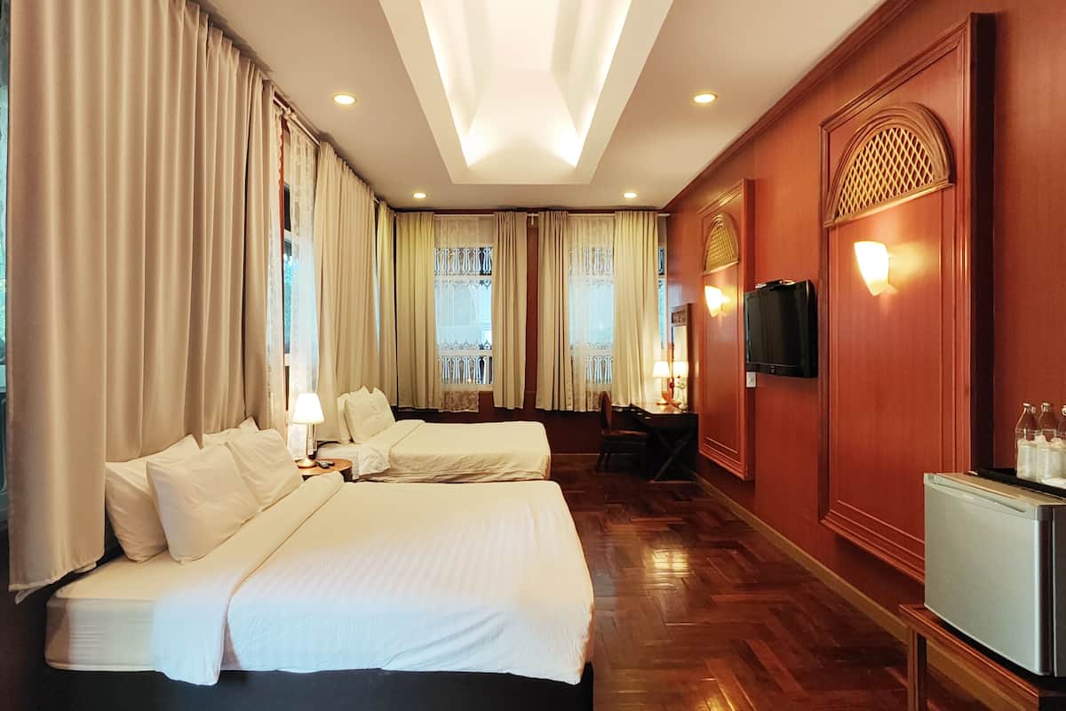 A hotel room with a large bed, a desk with a chair, a television, and a minibar.