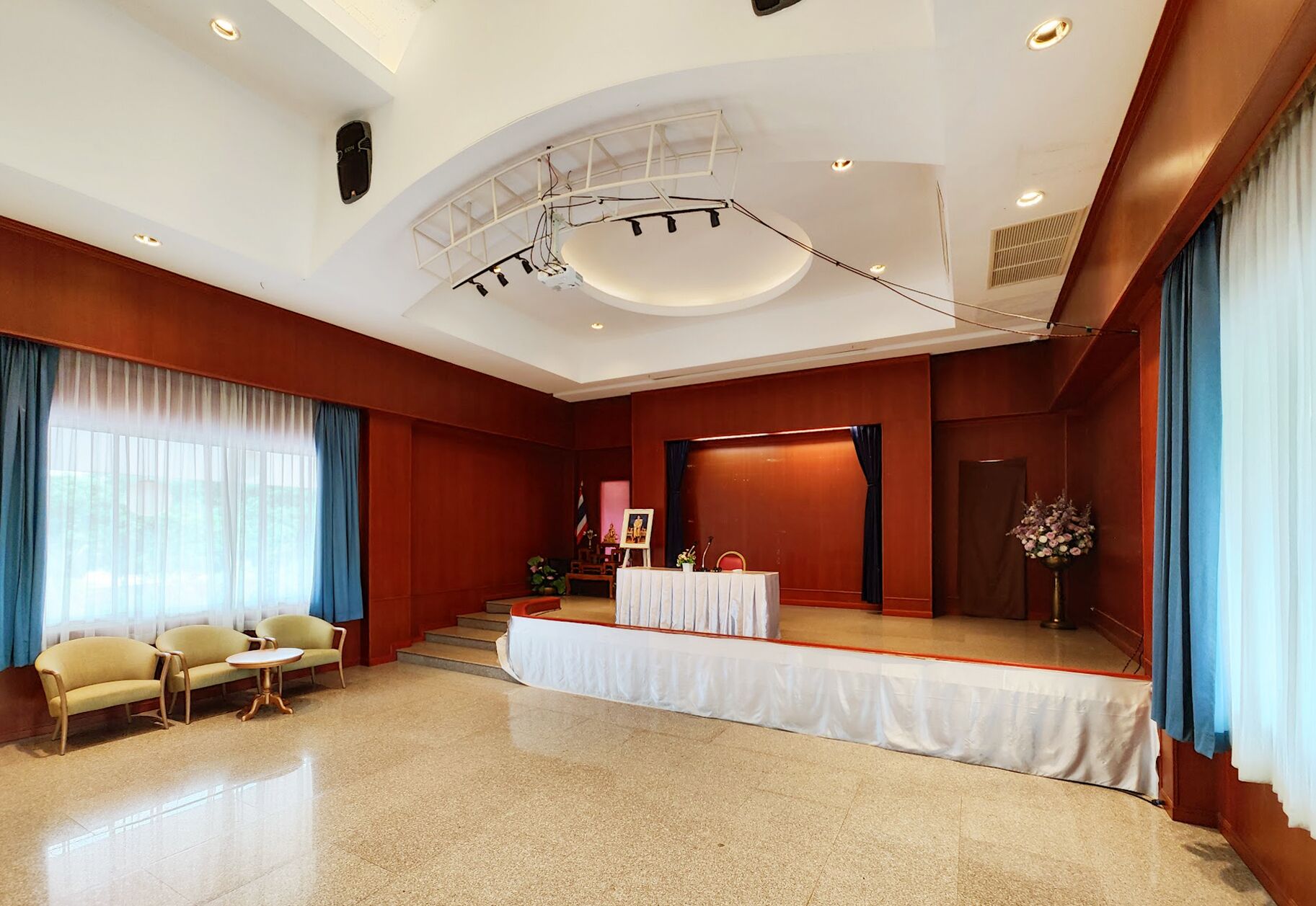 Ruime hotelkamer met een podium, een bank, een klein tafeltje en een groot raam met gordijnen.