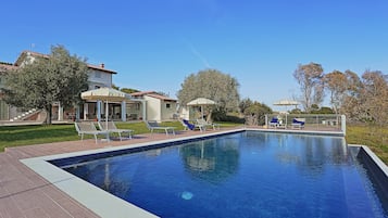 Una piscina techada, una piscina al aire libre, sombrillas