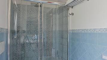 Une salle de bain avec une douche à parois de verre, des toilettes et un bidet.