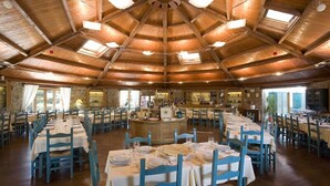 A large dining hall with high wooden ceilings and multiple tables set for dining. - Agriturismo Casale degli Ulivi (Alghero)