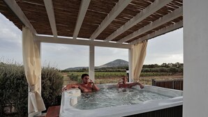 A hot tub with two people, surrounded by a wooden pergola and a scenic vineyard view. - Agriturismo Casale degli Ulivi (Alghero)