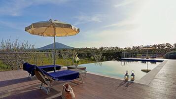 Una piscina techada, una piscina al aire libre, sombrillas