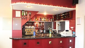 A bar area with a red counter, shelves of bottles, and a coffee machine. - Abbey Grange Hotel (Nuneaton)