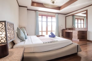 A modern bedroom with a large bed, a wooden desk, and a mirror.