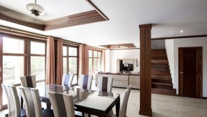 A spacious living area with a dining table and chairs, a sofa, and a staircase leading to another level. - 4 Bedroom Villa TG48 on beachfront resort SDV288-By Samui Dream Villas (Koh Samui)