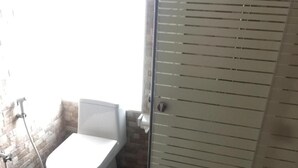 Kylpyhuone, jossa on wc, suihku ja lasiovi.