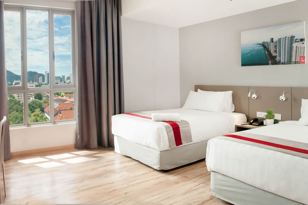 A hotel room with two beds, a desk, a TV, and a large window with a city view.