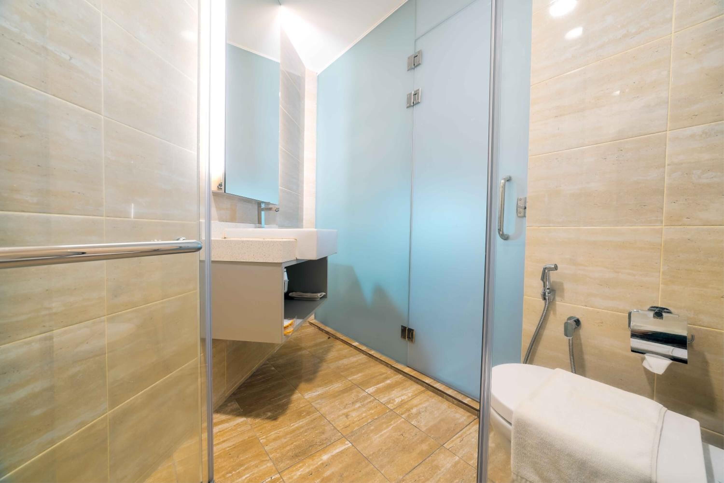 A modern bathroom with a glass shower enclosure, a white toilet, and a sink with a mirror.