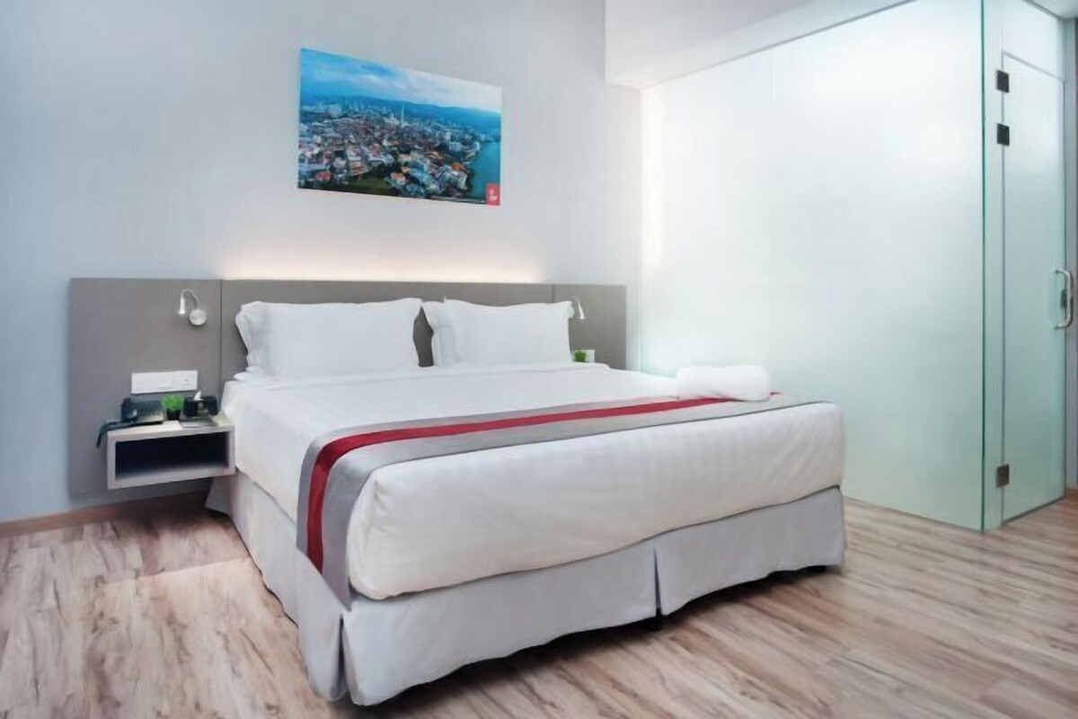 A modern hotel room with a large bed, a nightstand, a wardrobe, and a cityscape view.