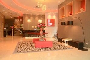 A hotel reception area with a modern design, featuring a reception desk, a decorative vase with flowers, and a patterned carpet. - Mei Hotel (George Town)