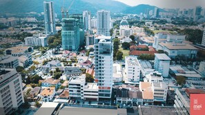 Un hotel de diseño moderno, rodeado de edificios residenciales y comerciales, con montañas al fondo.
