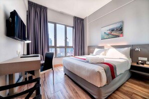 A hotel room with a bed, a desk, a chair, a TV, and a window with curtains. - Mei Hotel (George Town)