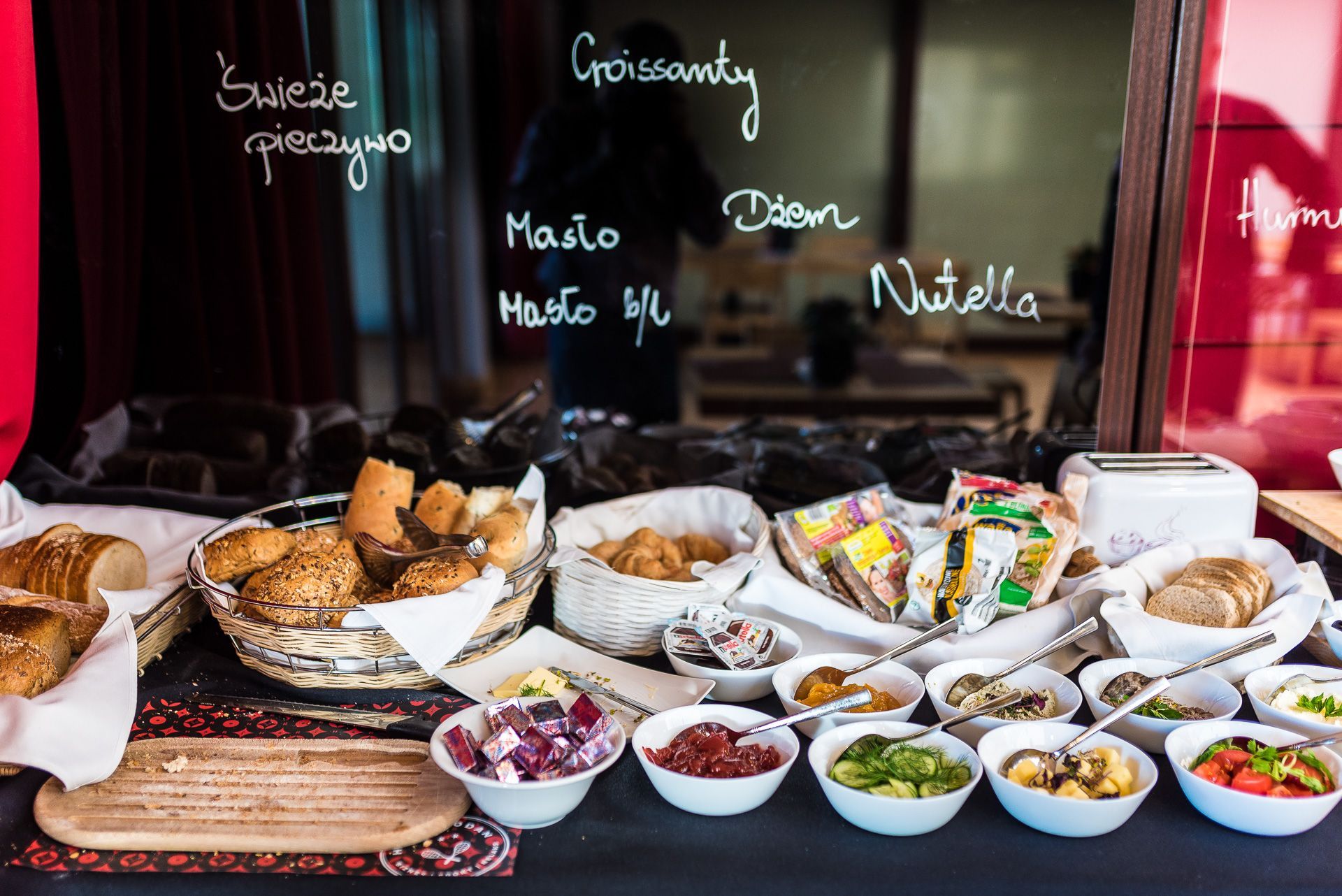 A variety of breads and spreads on a table, with baskets and bowls containing different food items.