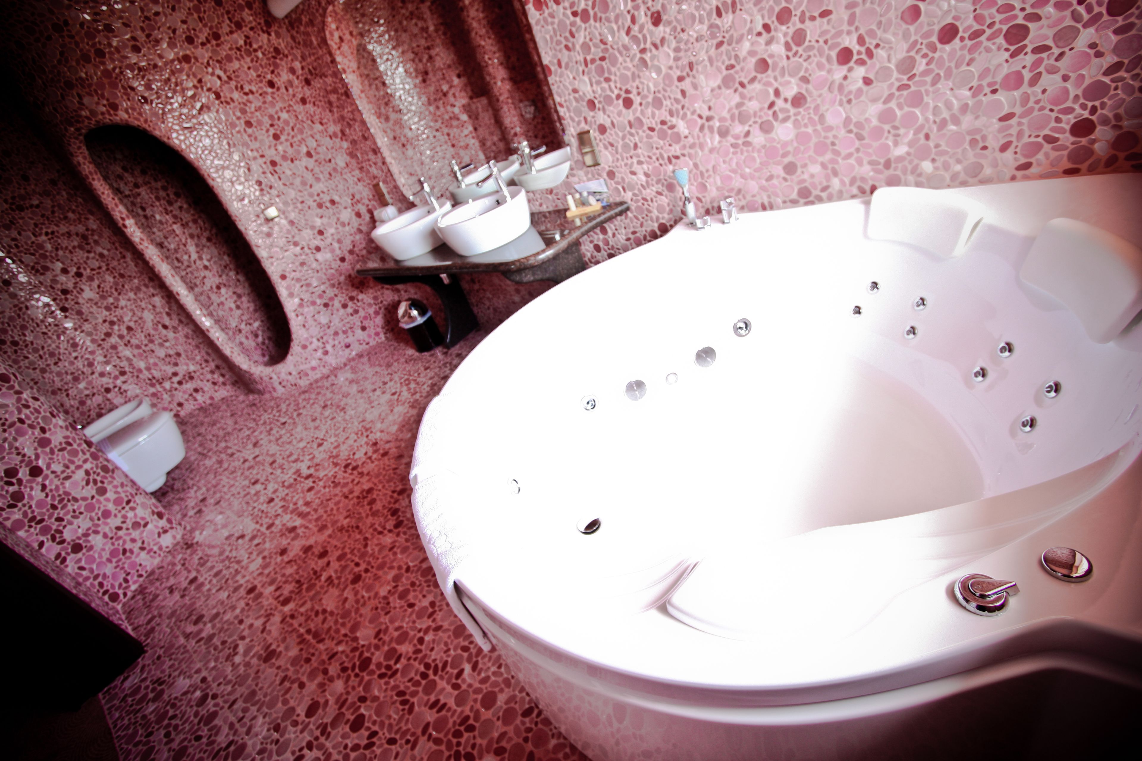 A spa bathroom with a large bathtub, multiple sinks, and a toilet.