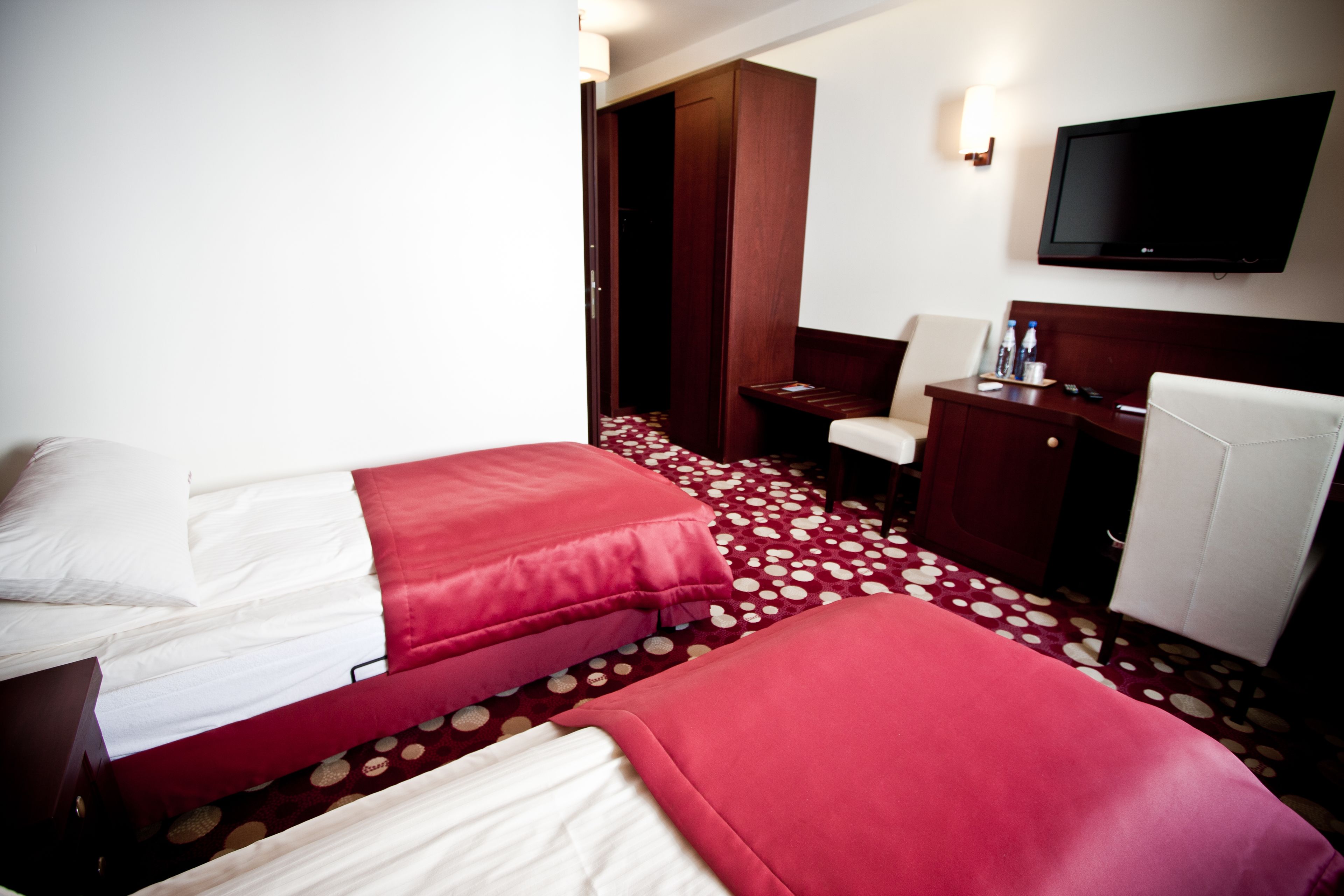 Une chambre d’hôtel avec deux lits, un bureau, une chaise, une télévision et une armoire.