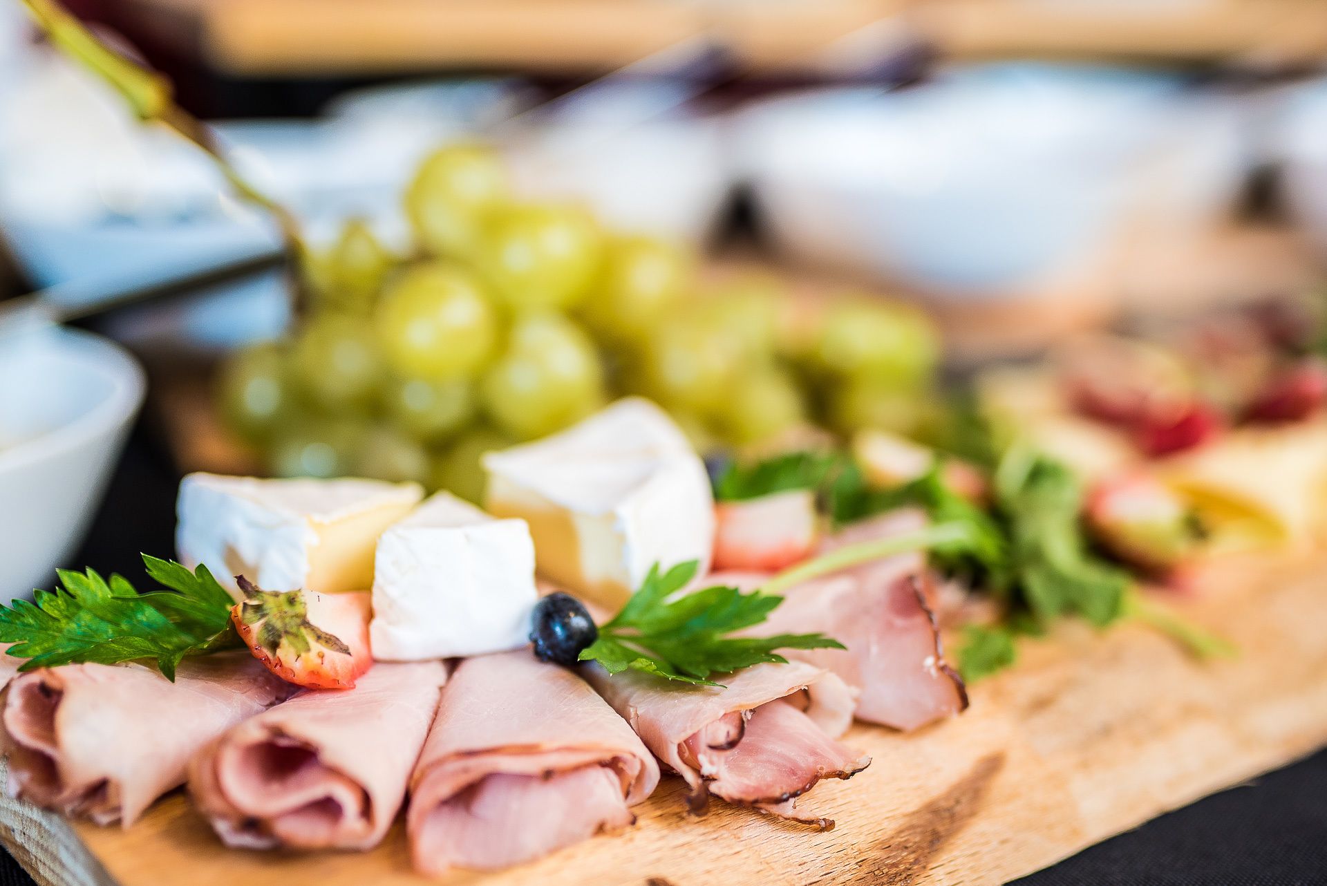Una tabla de embutidos con diferentes carnes, quesos y uvas.