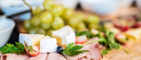 Una tabla de embutidos con diferentes carnes, quesos y uvas.
