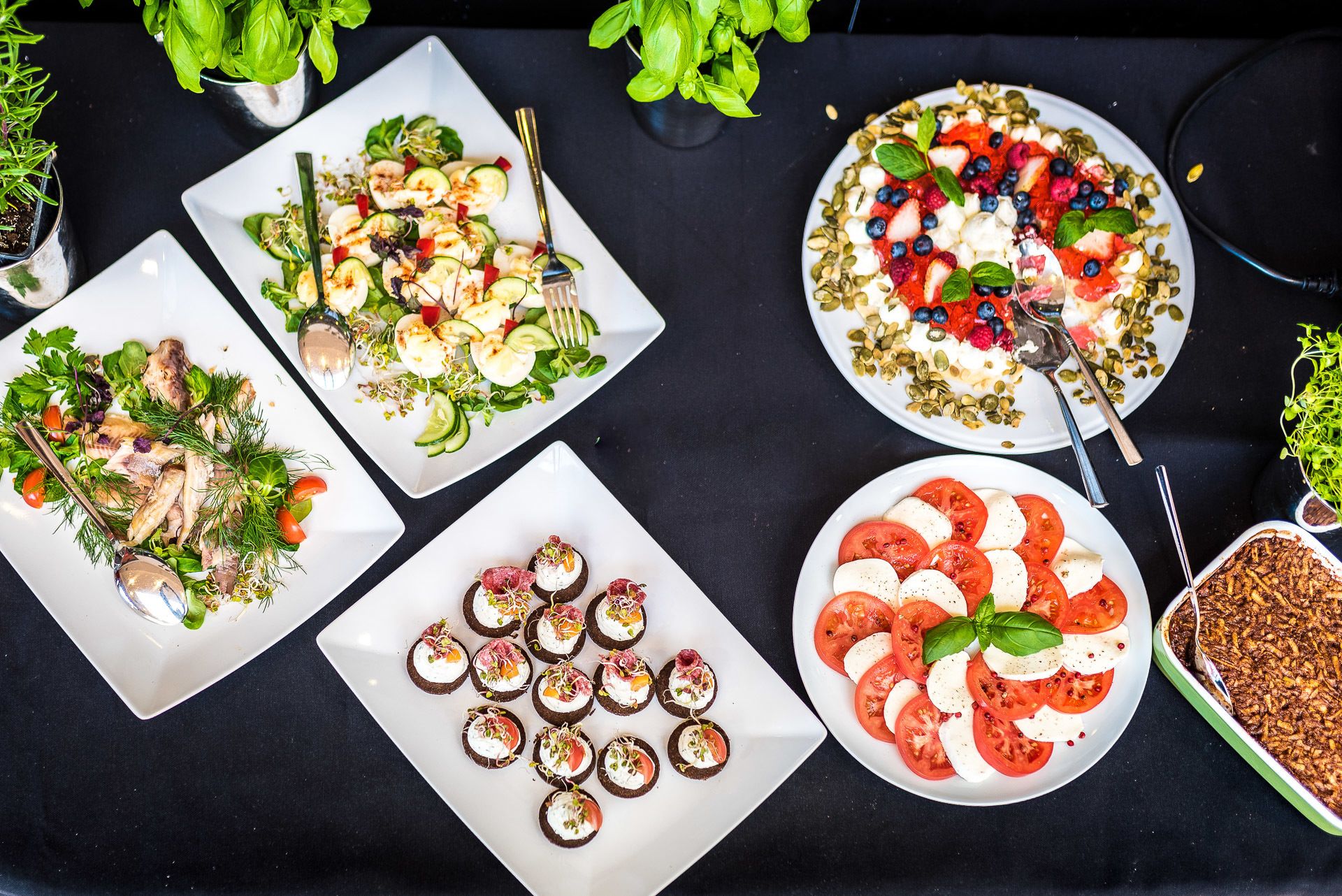 A variety of dishes on a table, including salads, bruschetta, and a tomato and mozzarella salad.