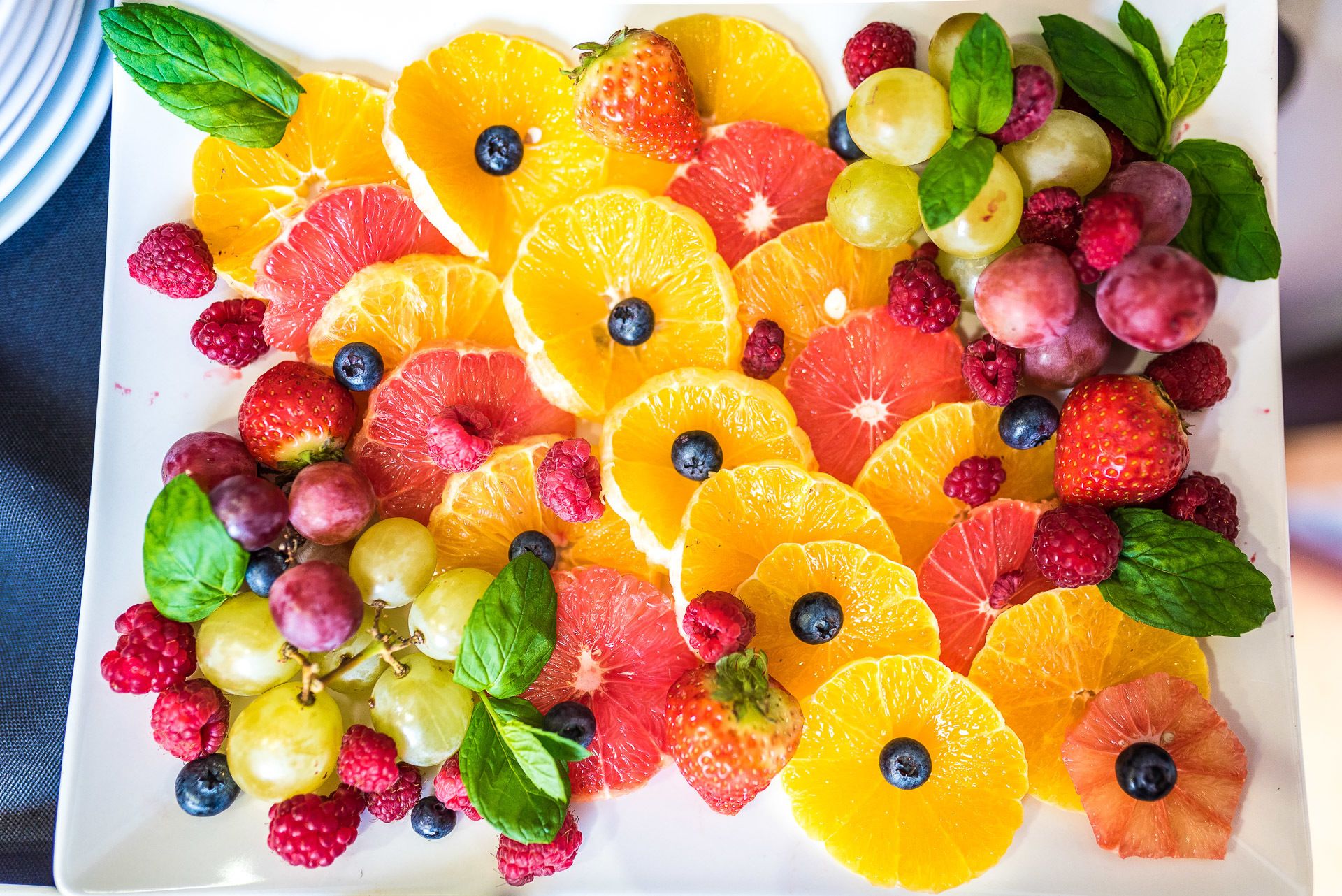 A fruit platter with various fruits and mint leaves.
