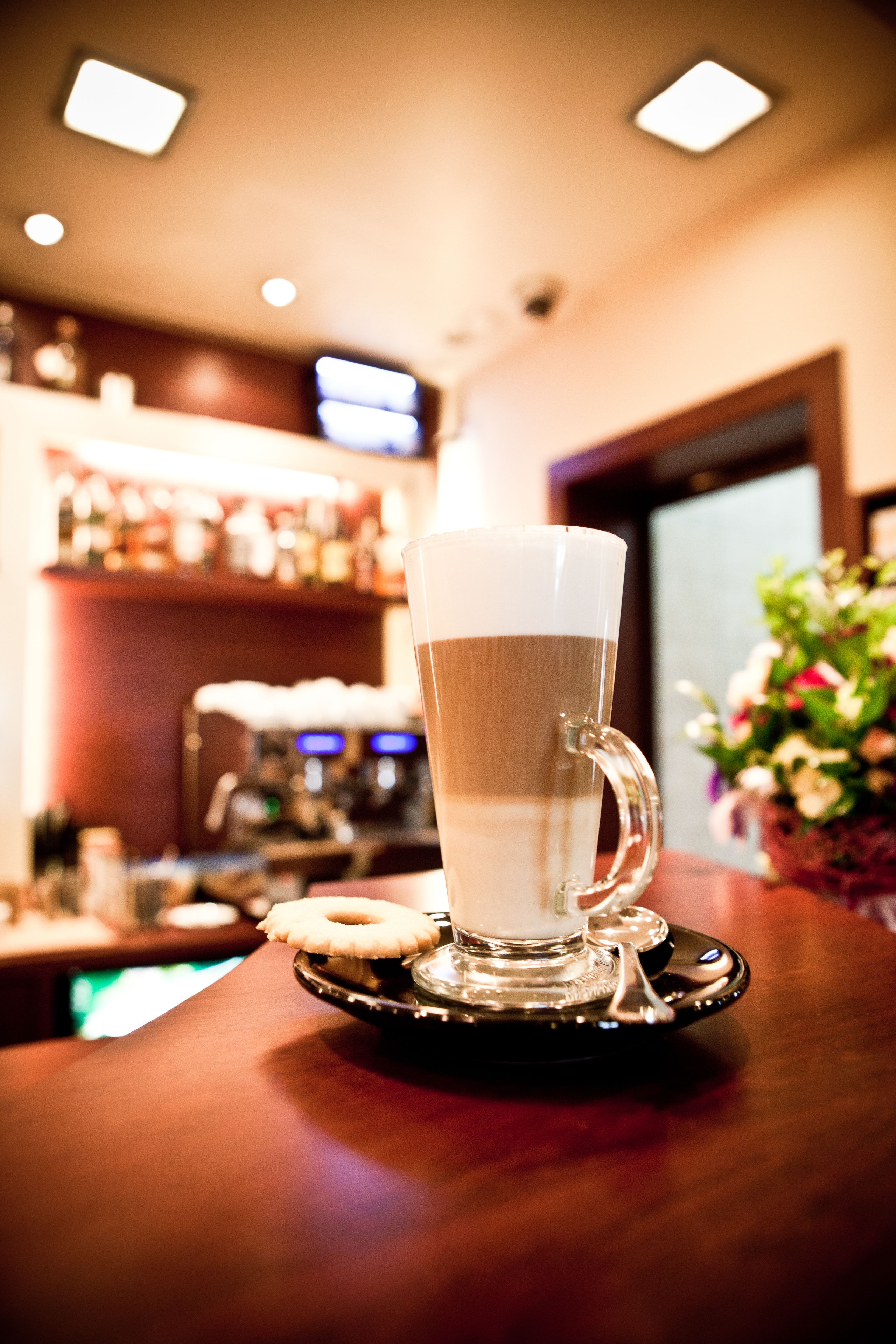 A clear glass cup with a handle on a coaster, placed on a wooden surface.