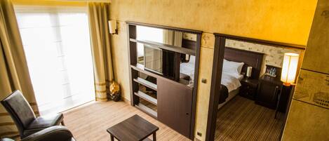 Habitación de hotel compacta con cama, una mesita, un sofá y un minibar.