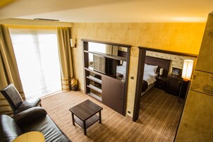Une chambre d’hôtel de taille réduite, comprenant un lit, une petite table, un canapé et un mini-bar.