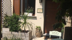 A courtyard with a wooden bench, potted plants, and a tiled floor. - B&B Il Rustico (Turate)