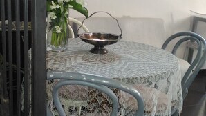 A round table with a lace tablecloth, a metal bowl, and a vase with flowers. - B&B Il Rustico (Turate)