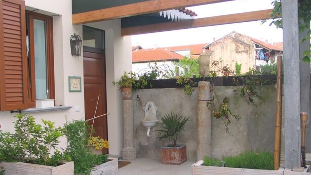 A courtyard with raised garden beds, a door, and a wall-mounted light fixture. - B&B Il Rustico (Turate)