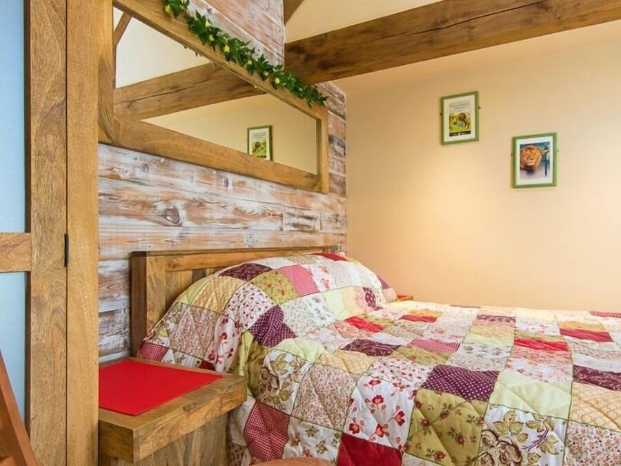 Un dormitorio con cabecera de madera, colcha acolchada y almohada roja.