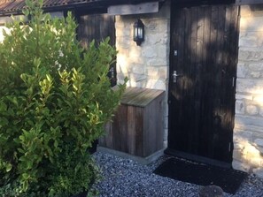 A stone building with a dark wooden door and a small wooden shed. - Widbrook Barns (Bradford-on-Avon)