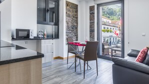 A modern kitchen with a microwave, a dining table with chairs, and a view of a street through a glass door.