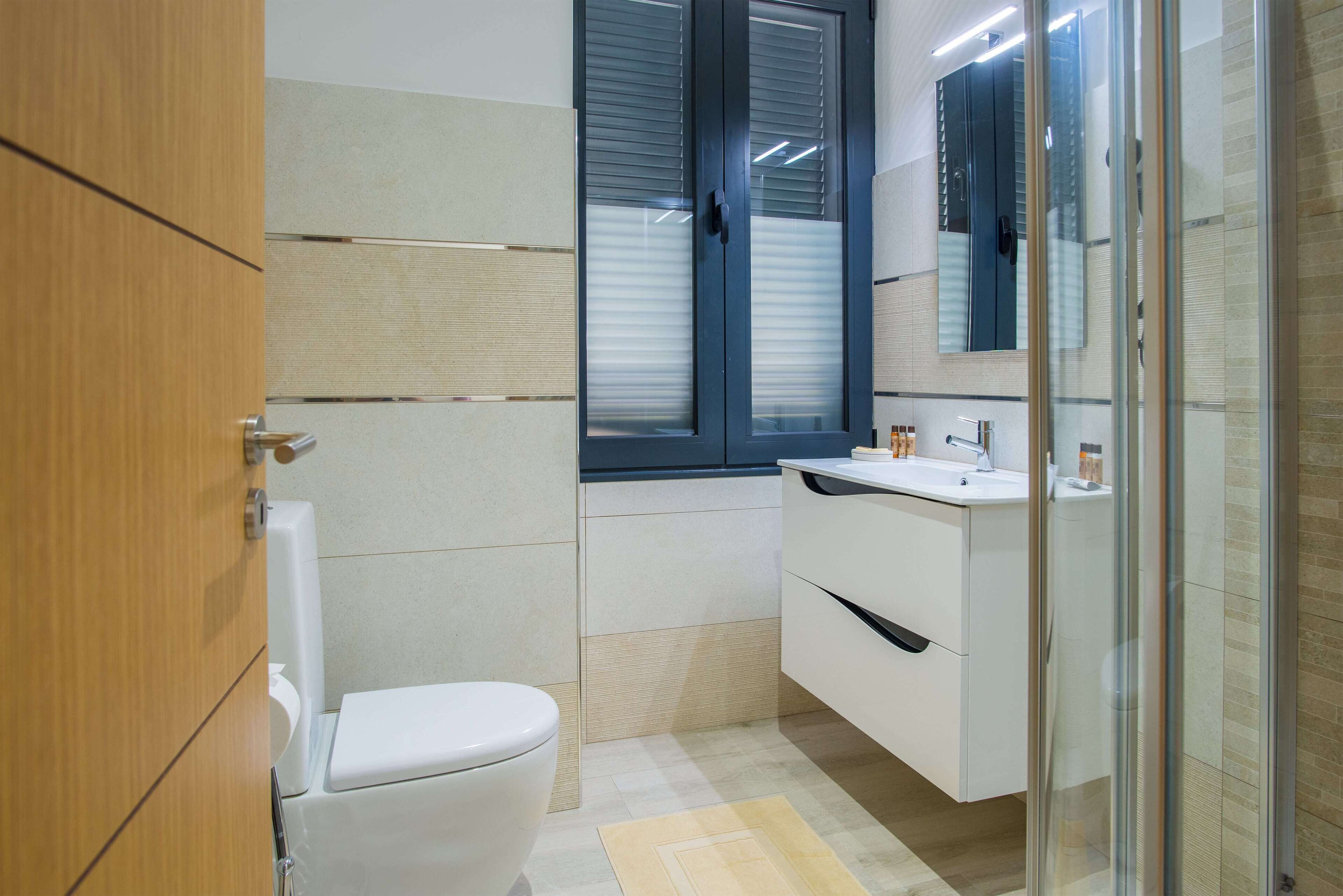 A modern bathroom with a toilet, a sink, and a glass shower enclosure.